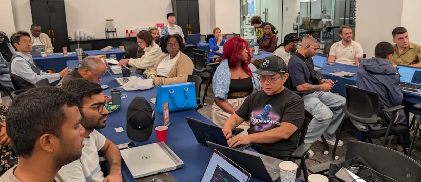Builders working on laptops around shared tables at a community meetup